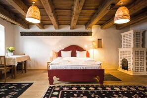 Un dormitorio con cama de madera, dos lámparas de noche, una chimenea y una zona de comedor con mesa y sillas.