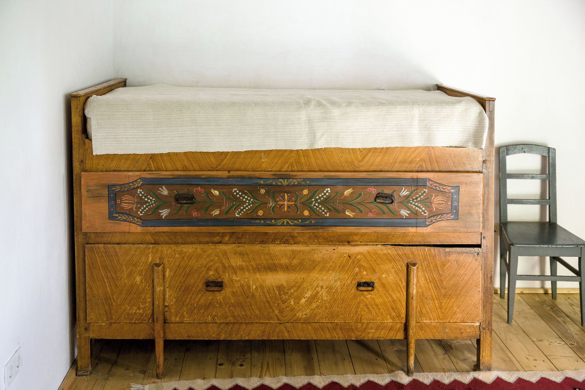 A wooden bed with a decorative headboard and a small chest of drawers below.