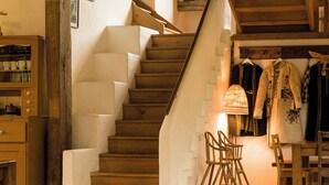 A wooden staircase leading to an upper floor, with a lamp and chairs on the landing. - Viscri 125 (Bunesti)