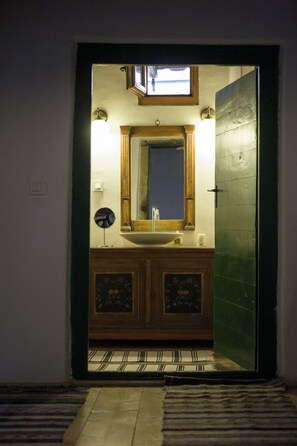 Un baño con tocador de madera, lavamanos y espejo.