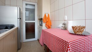 A compact kitchen with a refrigerator, a microwave, and a table with a checkered tablecloth. - Premium one-bedroom suite in the heart of Bucharest  (București)
