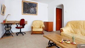 A living room with a wooden table, two chairs, a sofa, a cabinet, and a painting on the wall. - Premium one-bedroom suite in the heart of Bucharest  (București)