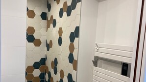 A modern bathroom with a geometric tile backsplash, a built-in shower, and a white vanity with a mirror. - Studio in Seguret. Lisanathis (Seguret)
