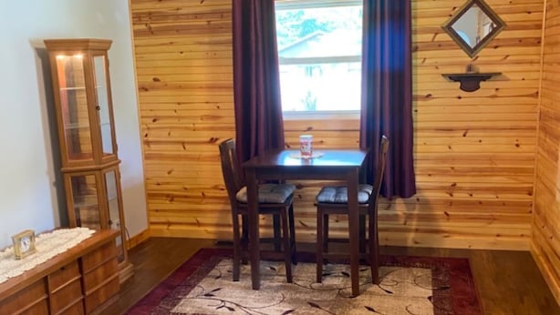 A wooden-paneled room with a dining table and chairs, a small cabinet, and a window with curtains. - Quaint, private setting, 3-4 miles from SOMC & KDMC hosp. (Portsmouth)