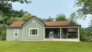 A two-story house with a green exterior and a brown roof, featuring a covered porch with outdoor seating. - Quaint, private setting, 3-4 miles from SOMC & KDMC hosp. (Portsmouth)