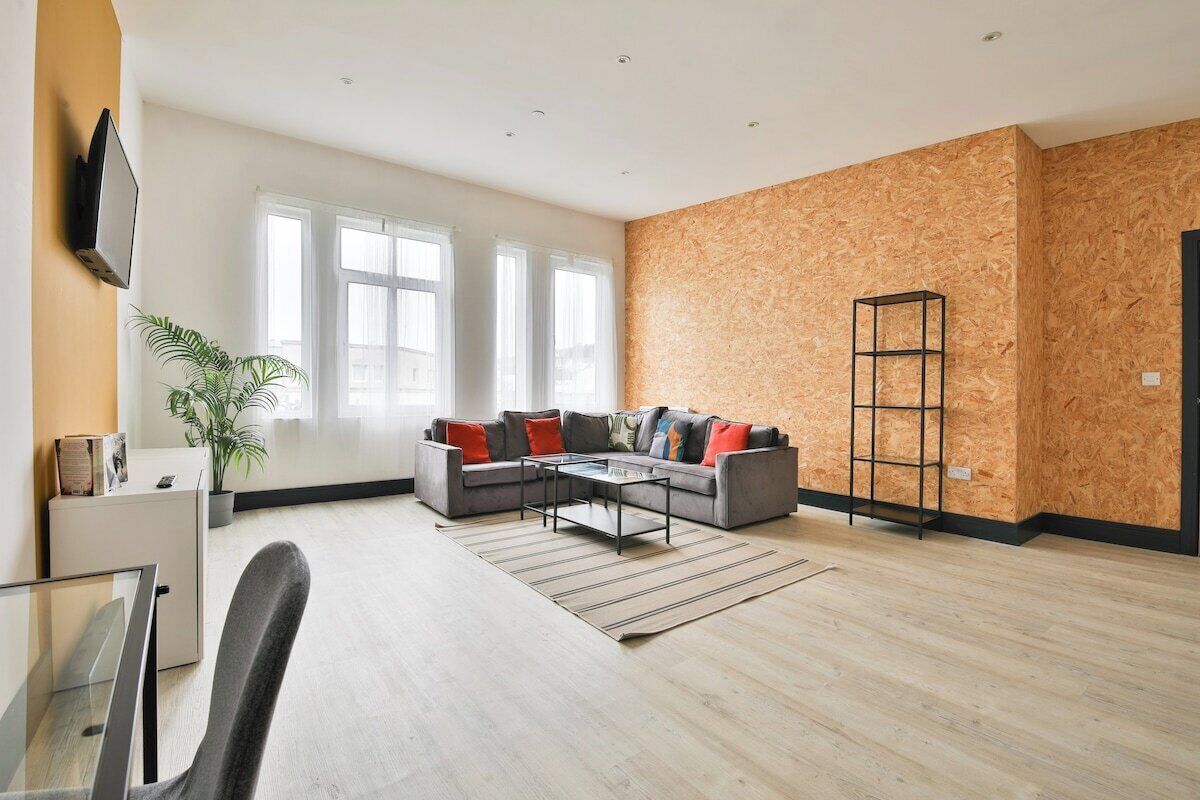 Una sala de estar moderna con un sofá gris, una mesa de centro y un televisor montado en la pared.
