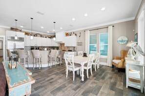 A modern kitchen with white cabinets, a central island, and pendant lighting. - Island Time Large Private Pool Luxury Super Close Beach Access (Panama City Beach)