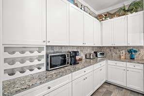A kitchen with white cabinets, a granite countertop, a built-in microwave, a coffee maker, and a toaster. - Large Private Pool Luxury Super Close Beach Access (Panama City Beach)
