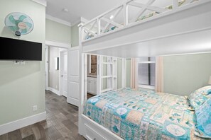 Ein Schlafzimmer mit Etagenbett, Deckenventilator und Blick zur Küche durch eine offene Tür.