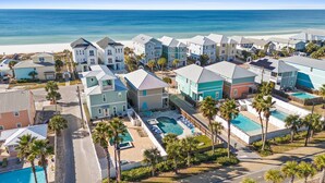 Una zona residenziale costiera con diverse case a due piani, una piscina e una spiaggia sullo sfondo.