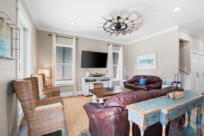 A living room with wicker furniture, a leather sofa, a wooden coffee table, and a ceiling fan. - Large Private Pool Luxury Super Close Beach Access (Panama City Beach)