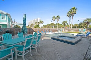 Un espace piscine comprenant des chaises longues, un jacuzzi et une table à manger avec des chaises.