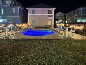 A residential pool area with lounge chairs and a small pool, surrounded by a wooden fence and string lights. - Large Private Pool Luxury Super Close Beach Access (Panama City Beach)