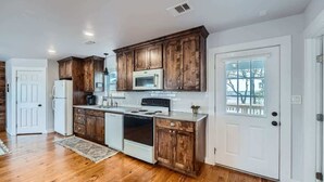 A kitchen with wooden cabinets, a microwave, stove, and refrigerator. - Wilbarger Villa-Sunsets Overlooking SWU & Downtown (Georgetown)