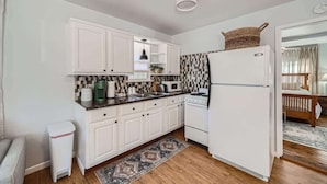 A compact kitchen with white cabinets, a microwave, a stove, and a refrigerator.