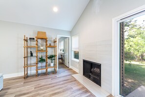 Ein modernes Wohnzimmer mit einem Holzregal, einem Kamin und Blick ins Freie.