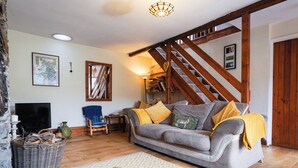 A cozy living room with a sofa, a television, a bookshelf, and a staircase. - Delfryn, Goginan (Aberystwyth)