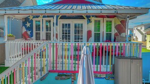 A house with a colorful exterior, a porch with a railing, and a small deck area. - ROUND HOUSE SANDUSKY. Heated inground pool, your own oasis! (Sandusky)