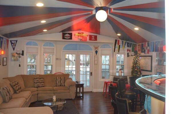 A living room with a large window, a bar area, and a sign indicating a whiskey exit. - ROUND HOUSE SANDUSKY. Heated inground pool, your own oasis! (Sandusky)