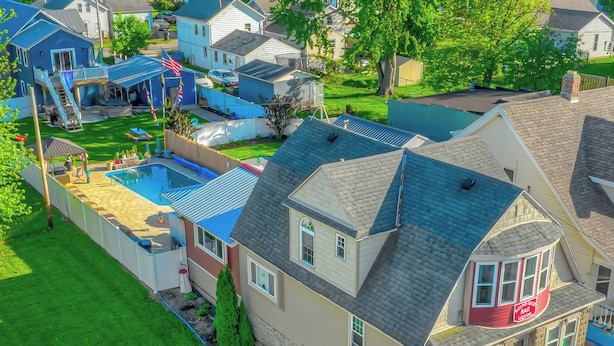 A residential area with a house featuring a large front yard, a swimming pool, and a small deck area. - ROUND HOUSE SANDUSKY. Heated inground pool, your own oasis! (Sandusky)