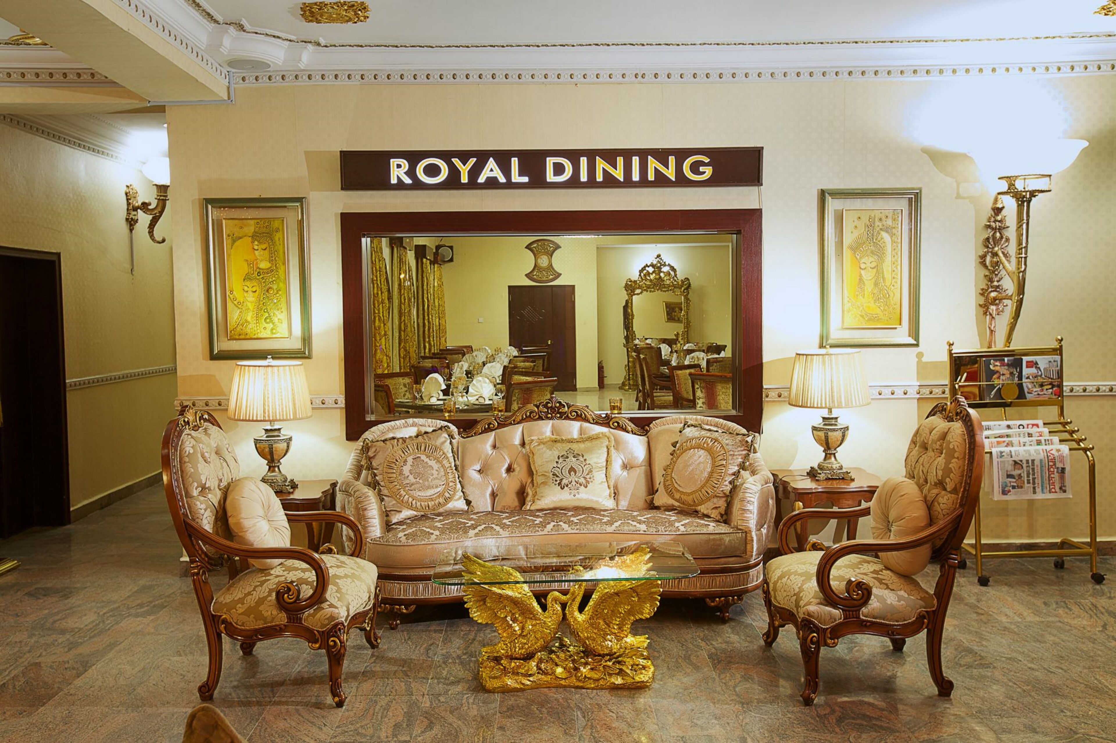 Una habitación lujosa con un cartel que dice 'ROYAL DINING', muebles ornamentados y un candelabro.