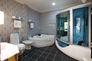 A modern bathroom with a jacuzzi, toilet, bidet, and glass-enclosed shower.