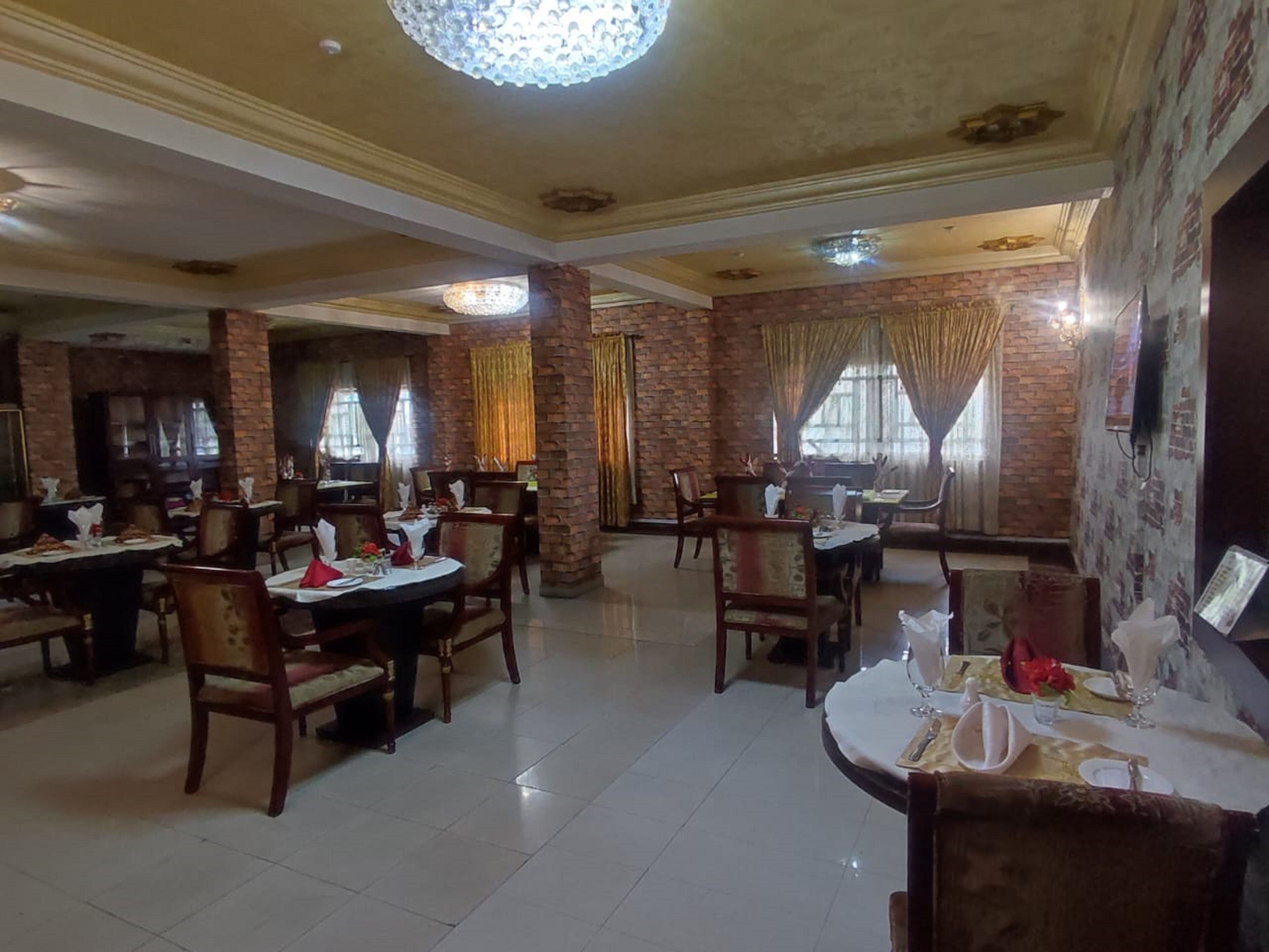 A spacious restaurant with brick walls, wooden tables, and chairs.