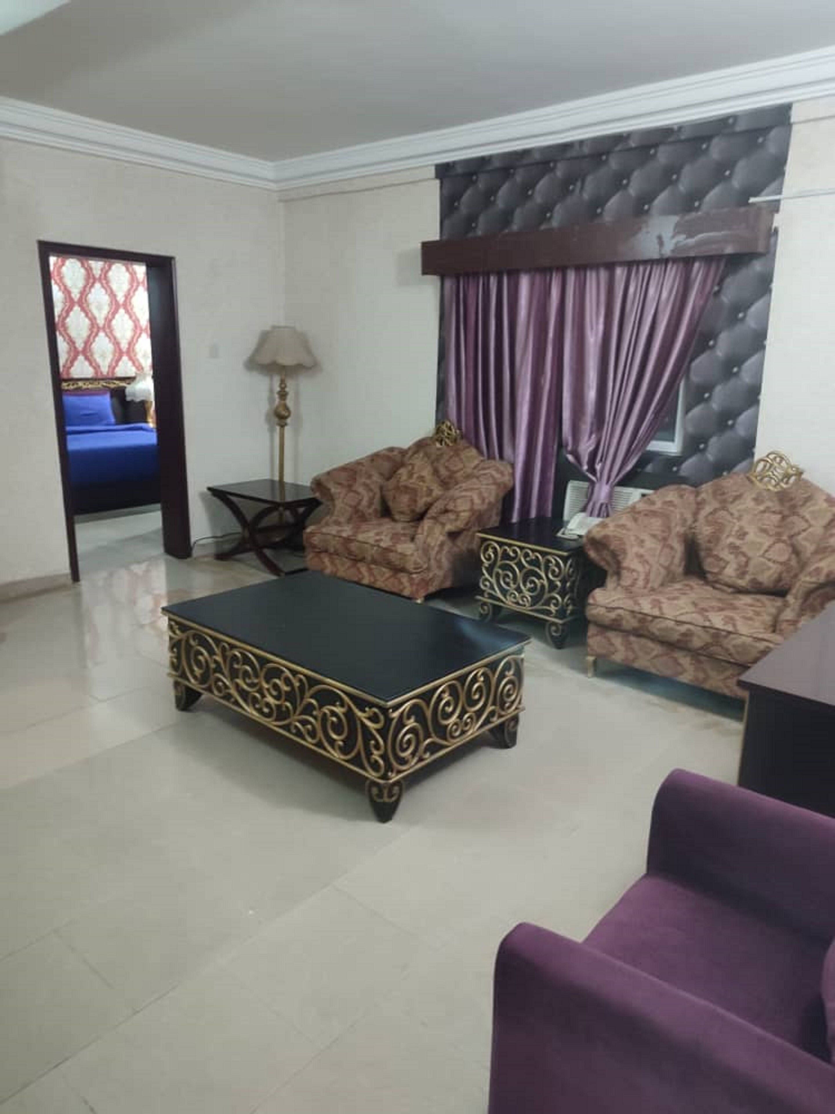 A living room with patterned sofas, a black coffee table, and a purple armchair.