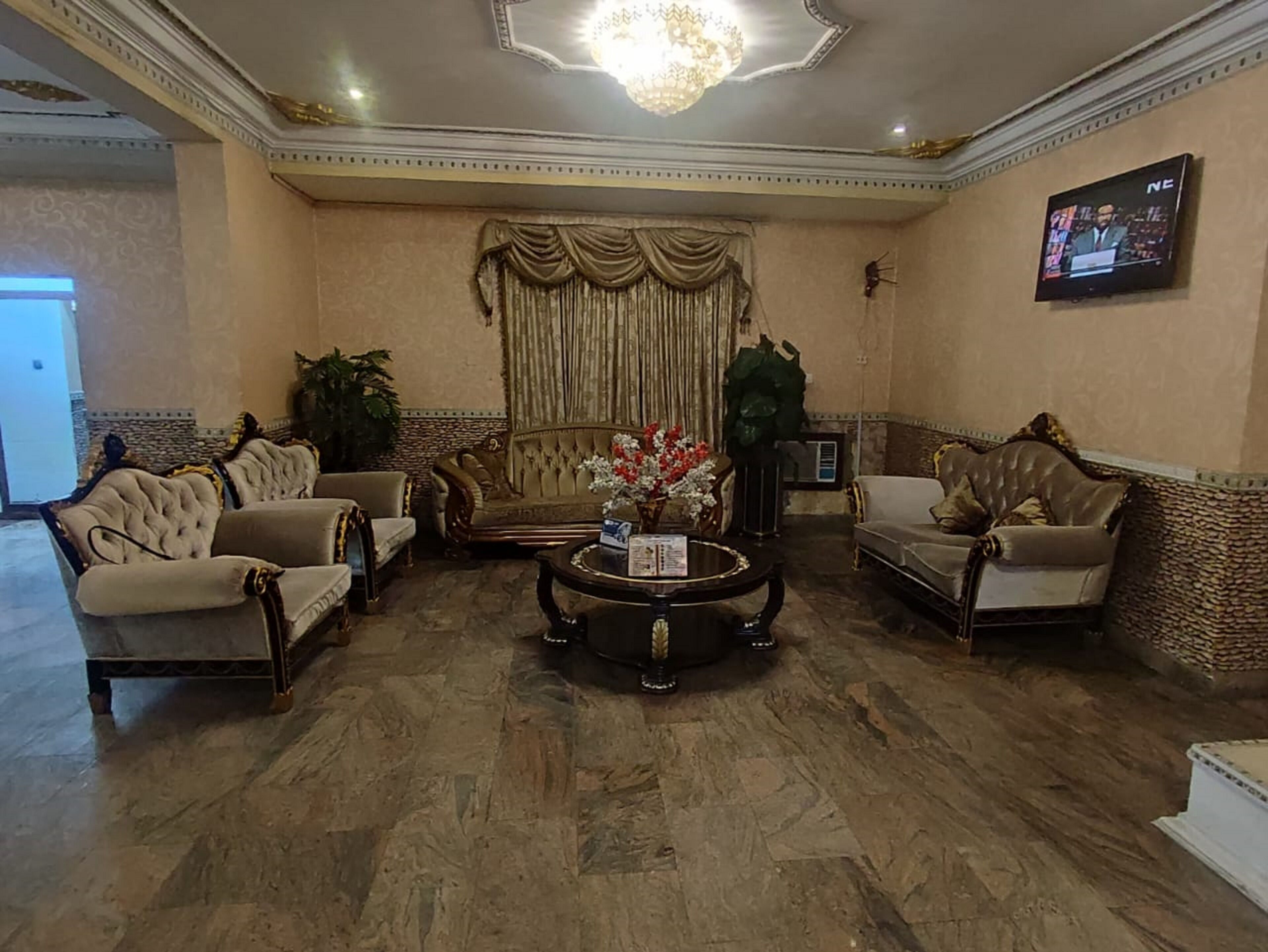 A spacious living room with a large sofa set, a coffee table, and a television mounted on the wall.