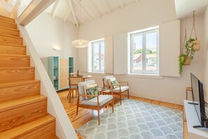 A spacious living area with a wooden staircase, a sofa set, a coffee table, and a television. - D&S -JB Apartments - C (Oporto)