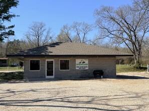 A small, single-story building with a gravel driveway, a door, and windows. - Current River Luxury in a Camper (Van Buren)