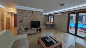 Un salón amplio con un televisor de pantalla plana, una mesa de centro de madera y un sofá cómodo.