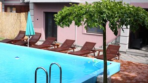 Una piscina con sillas de descanso y un árbol en el centro.