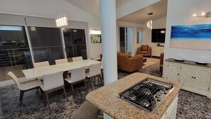 Una cocina moderna con encimeras de granito, una isla central y un comedor con sillas blancas.