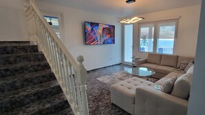 Una sala de estar con una escalera, un sofá, una mesa de centro y un cuadro en la pared.