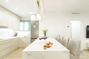 Enjoy meals in the spacious kitchen and dining area, featuring a central island, light cabinetry, and a long dining table.