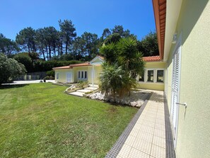 Ein zweistöckiges Haus mit geflieste Terrasse und einem gepflegten Rasen.