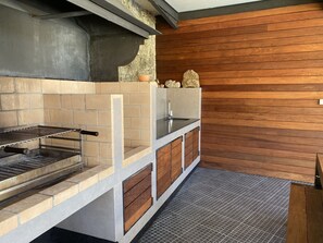 Eine moderne Außenküche mit integriertem Grill, Steinverzierungen und Holzverkleidung.