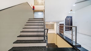 A staircase with a handrail, a fire extinguisher, and a door with a number.