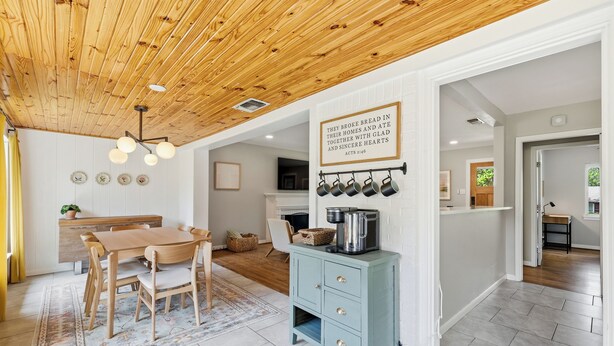 A modern kitchen with wooden ceiling, a dining area, and a blue cabinet with kitchen utensils. - Modern & Cozy 3BR near UTA/AT&T (Arlington)