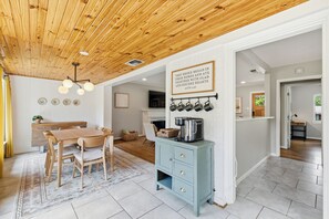 A modern kitchen with wooden ceiling, a dining area, and a blue cabinet with kitchen utensils.