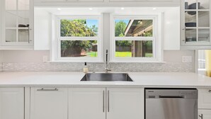 A modern kitchen with white cabinetry, a stainless steel sink, and a dishwasher. - Modern & Cozy 3BR near UTA/AT&T (Arlington)