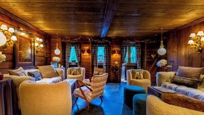 A cozy, wood-paneled room with plush seating, ambient lighting, and a staircase leading to another level. - Chalet Bragard - Boutique Chalet & Spa (Limone Piemonte)