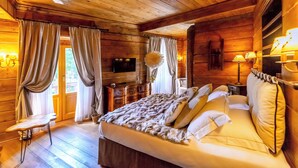 Un dormitorio de cabaña de madera con una cama, cortinas, un televisor de pantalla plana y una lámpara.