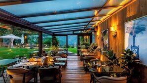 An indoor dining area with tables and chairs, a glass ceiling, and a view of the outdoors. - Chalet Bragard - Boutique Chalet & Spa (Limone Piemonte)