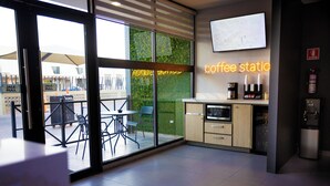 En moderne kaffestation med glasvæg, et på væggen monteret TV og en brandslukker til højre.