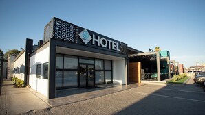 Et moderne hotel med et tydeligt skilt, store vinduer og et belagt indgangsparti.