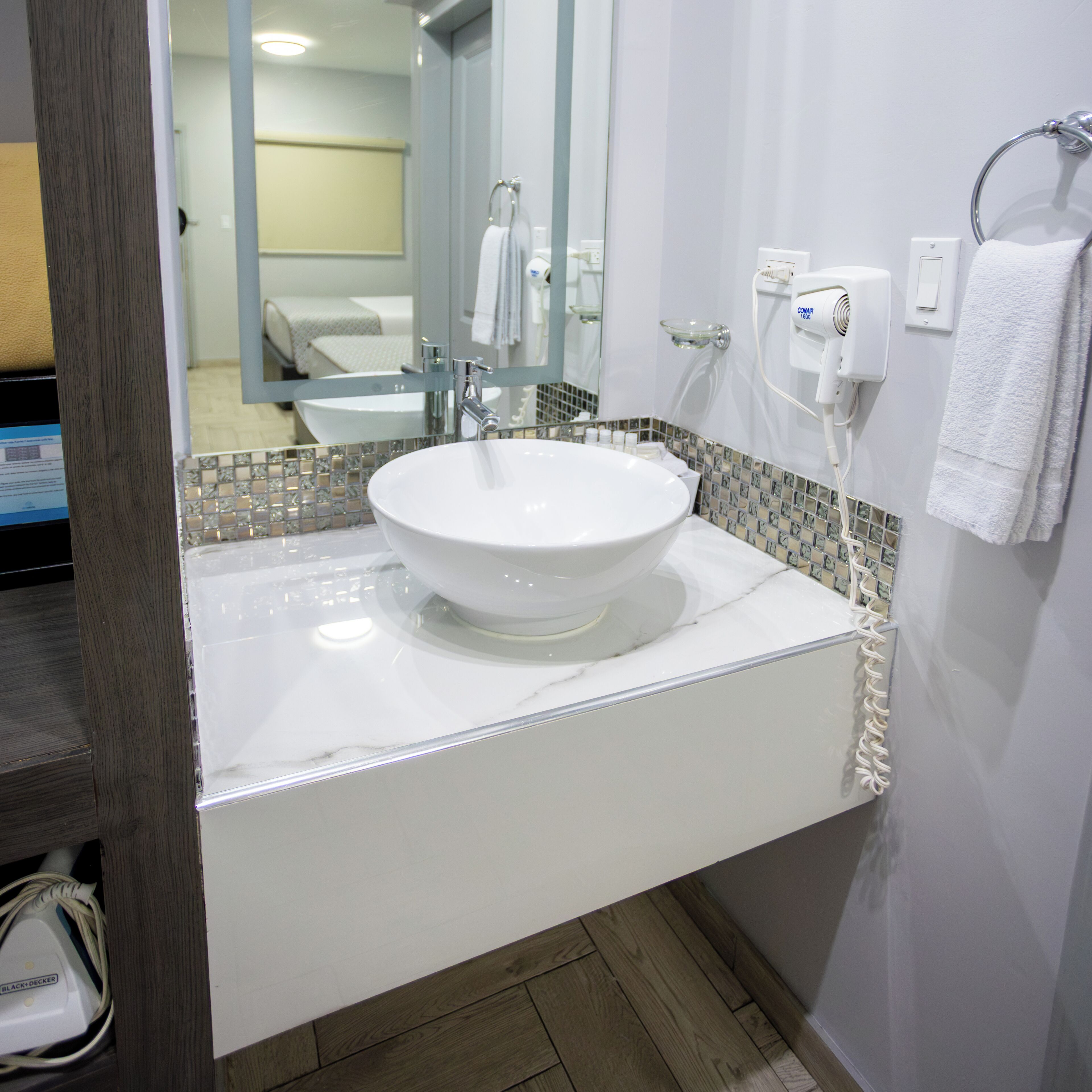 Un baño moderno con un lavamanos blanco, cabina de ducha con mampara de vidrio y un espejo.
