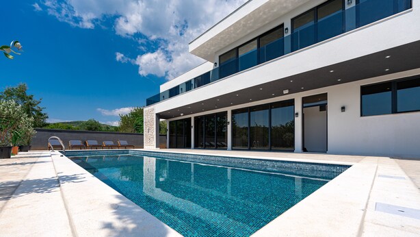 A modern building with a swimming pool, large windows, and a flat roof.