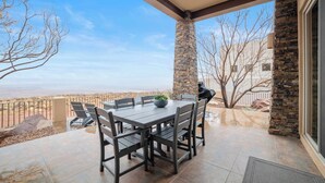 Une terrasse extérieure avec une colonne en pierre, une table avec des chaises et une vue sur le paysage.